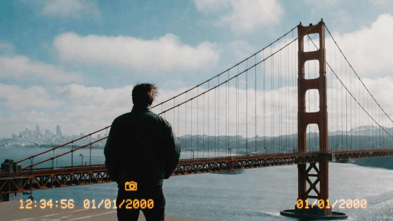 Person facing the Golden Gate Bridge with a camera icon and timestamp across the photo
